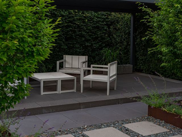 Shaded outdoor seating under a pergola with stepping stones